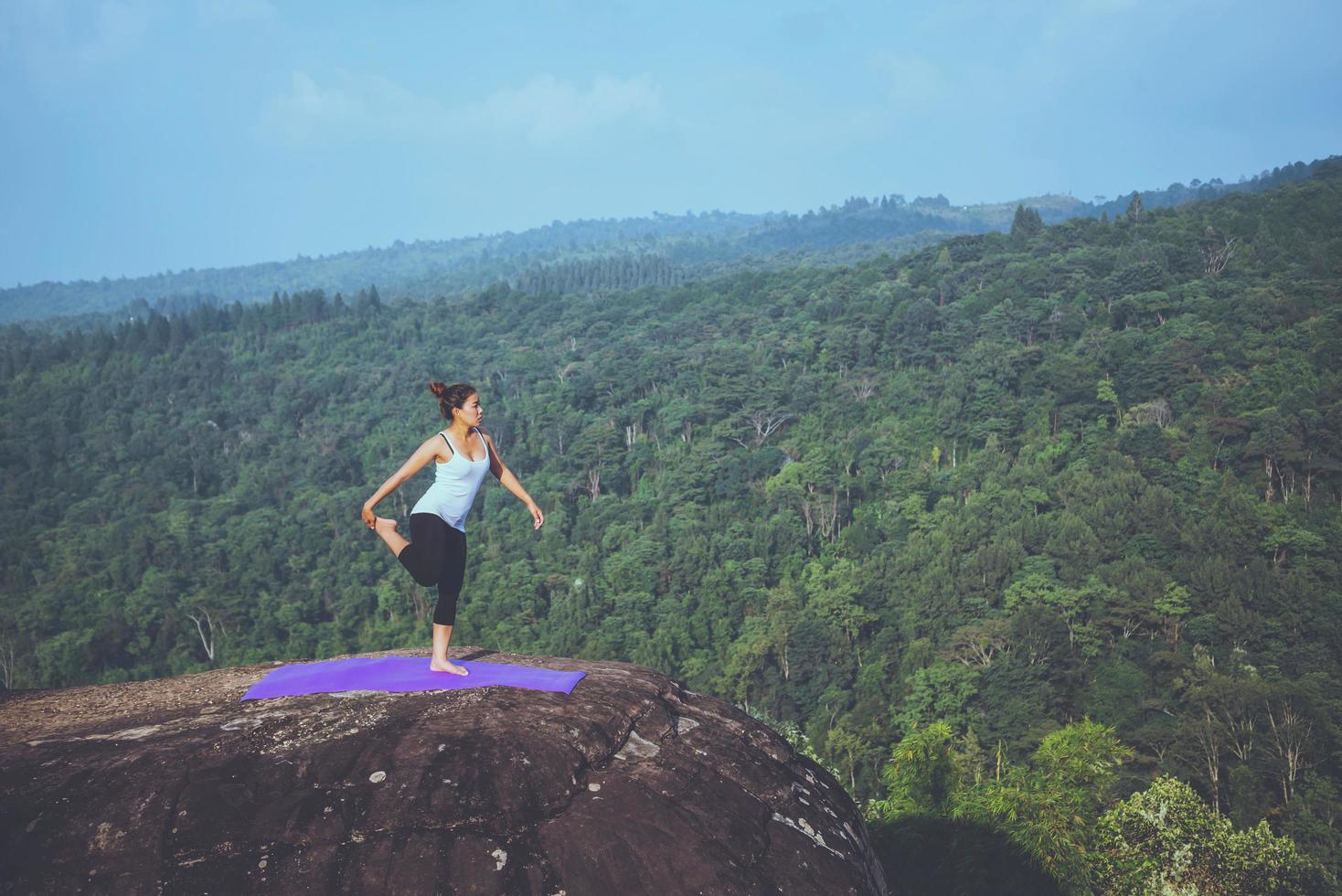 le donne asiatiche si rilassano durante le vacanze. gioca se lo yoga. sulla rupe rocciosa della montagna. natura delle foreste di montagna in thailandia foto