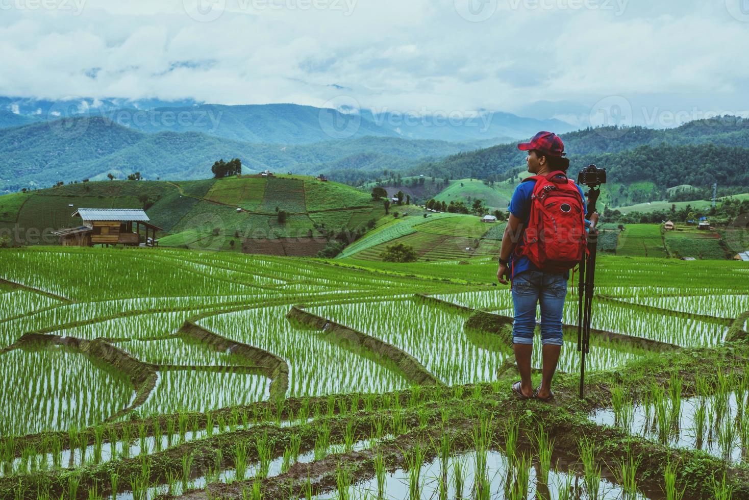 gli asiatici dell'uomo viaggiano nella natura. viaggiare rilassati. camminando scatta una foto sul campo. in estate.