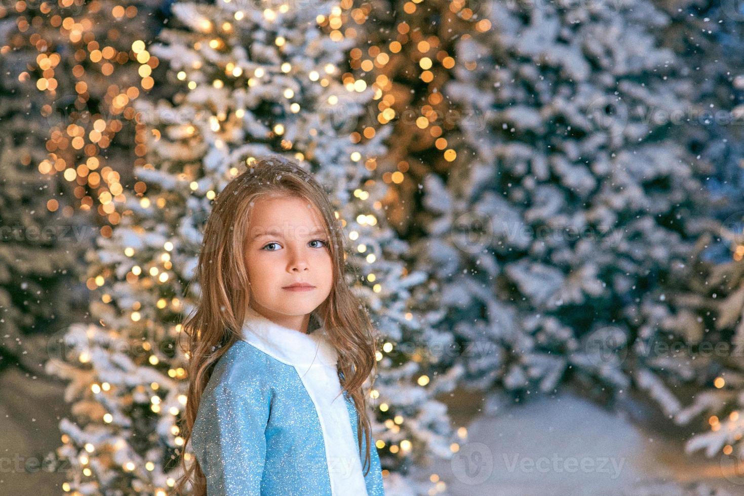 carina ragazza bionda caucasica che cammina nella foresta di natale invernale con luci. anno nuovo, concetto di fiaba foto