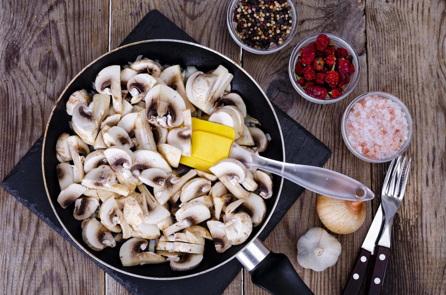 funghi prataioli crudi affettati in padella sulla tavola di legno. foto in studio