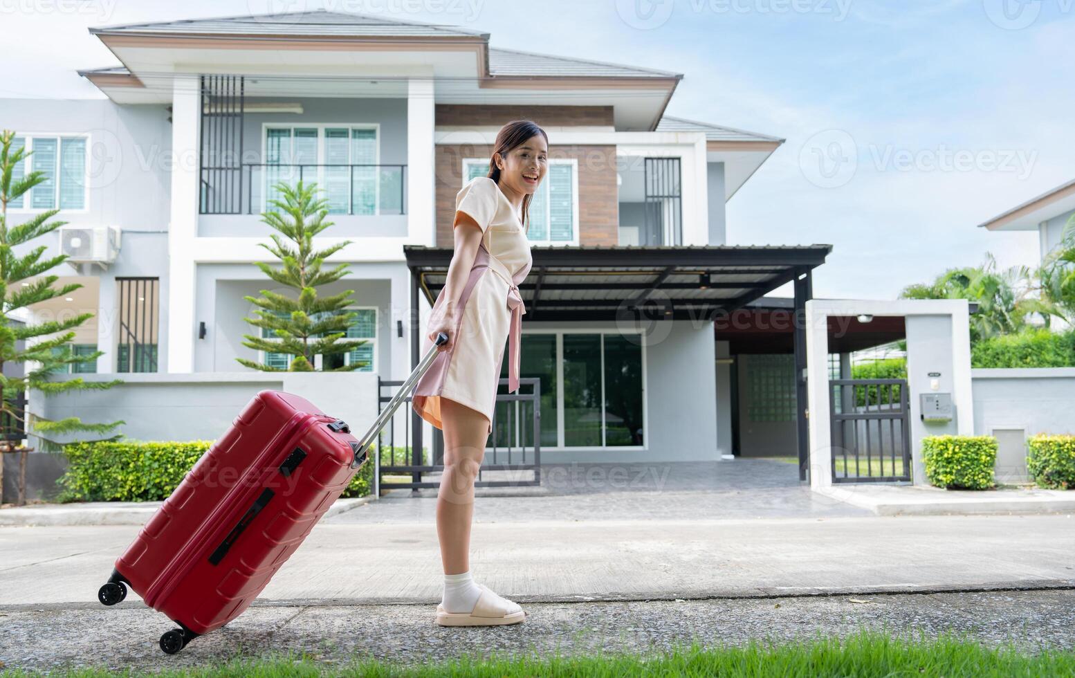 un' giovane asiatico donna con bagaglio in piedi nel davanti di un' nuovo acquisto casa per mossa in un' nuovo Casa. inizio vita a proprio o affittato piatto concetto e in movimento giorno concetto. foto