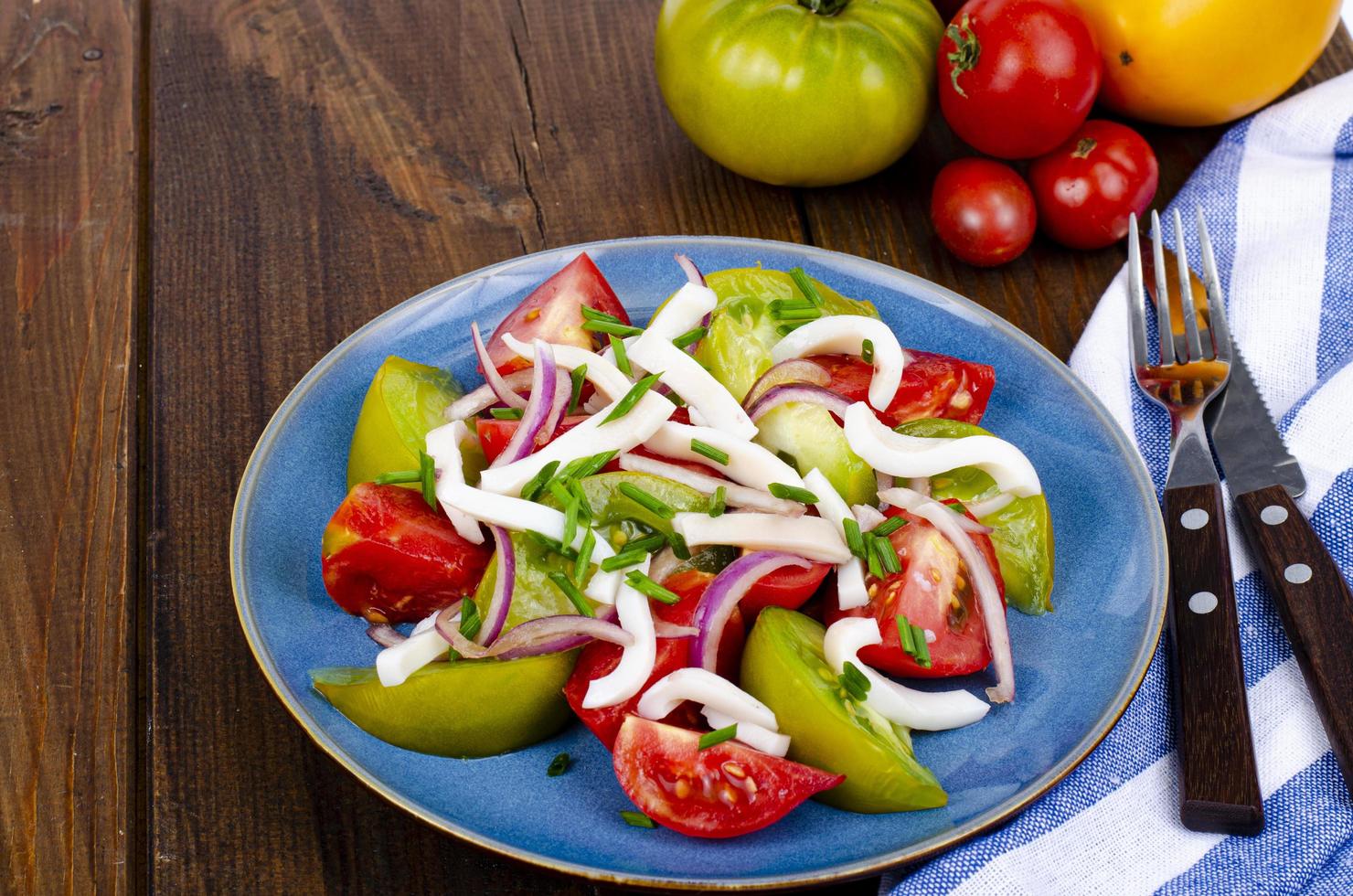 sana insalata di verdure con pomodori e pezzi di calamari. foto in studio.