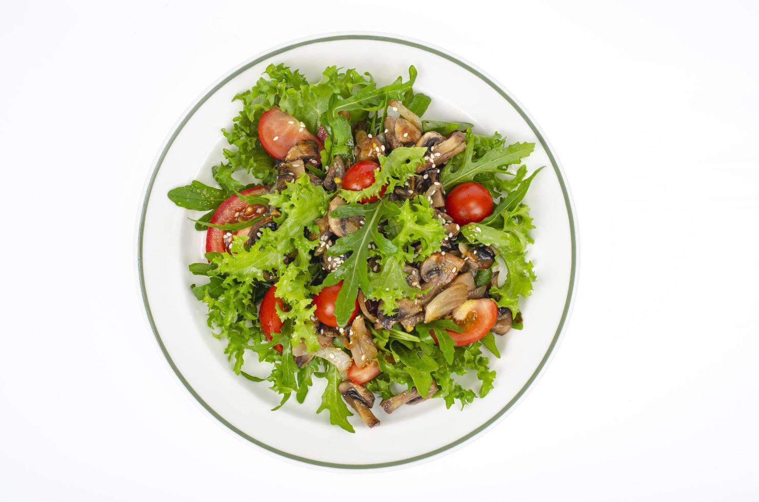 piatto con piatto vegetariano di rucola, pomodori e funghi su sfondo bianco. foto in studio