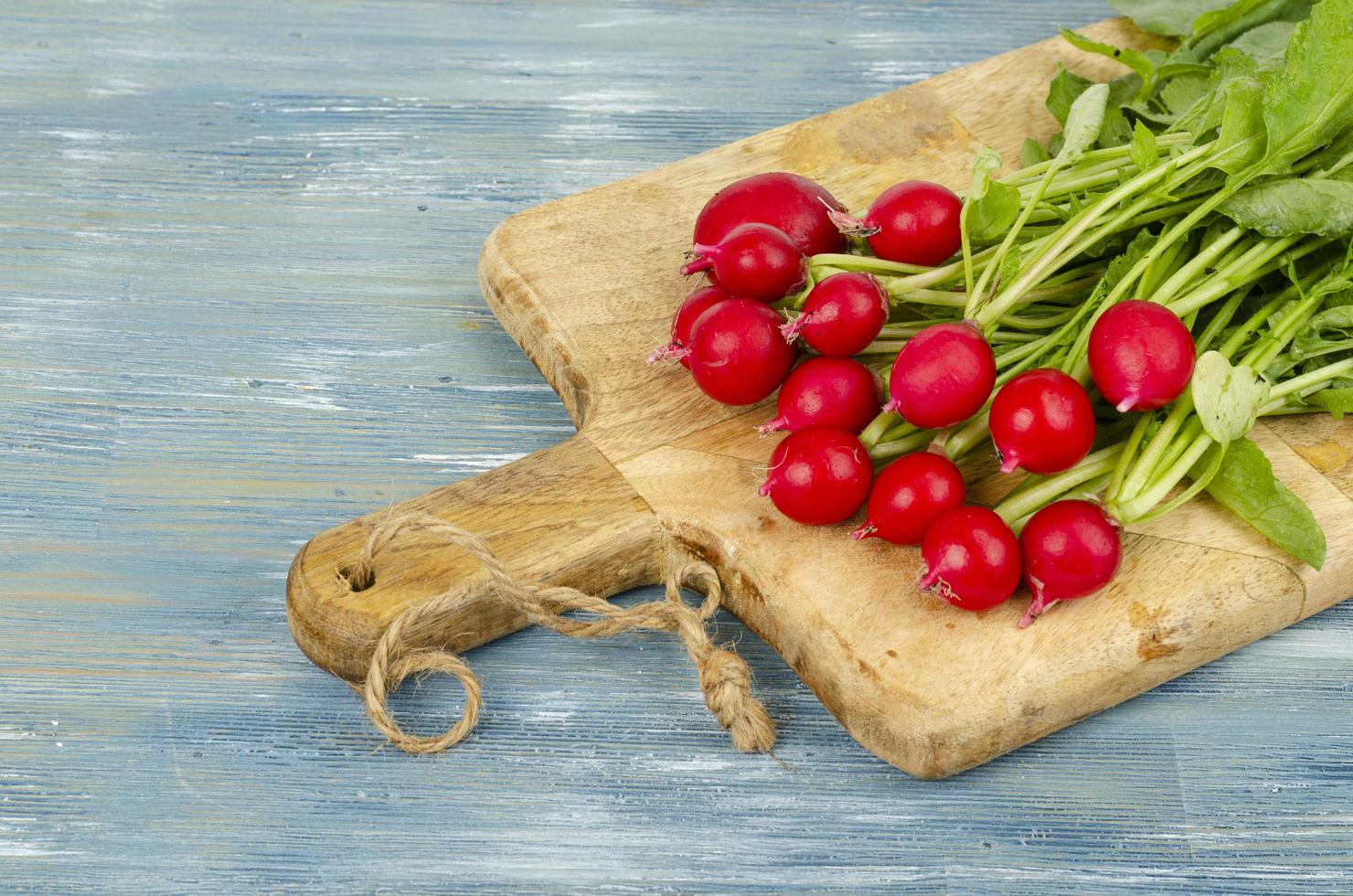 mazzo di ravanelli freschi sul tagliere di legno della cucina. foto in studio