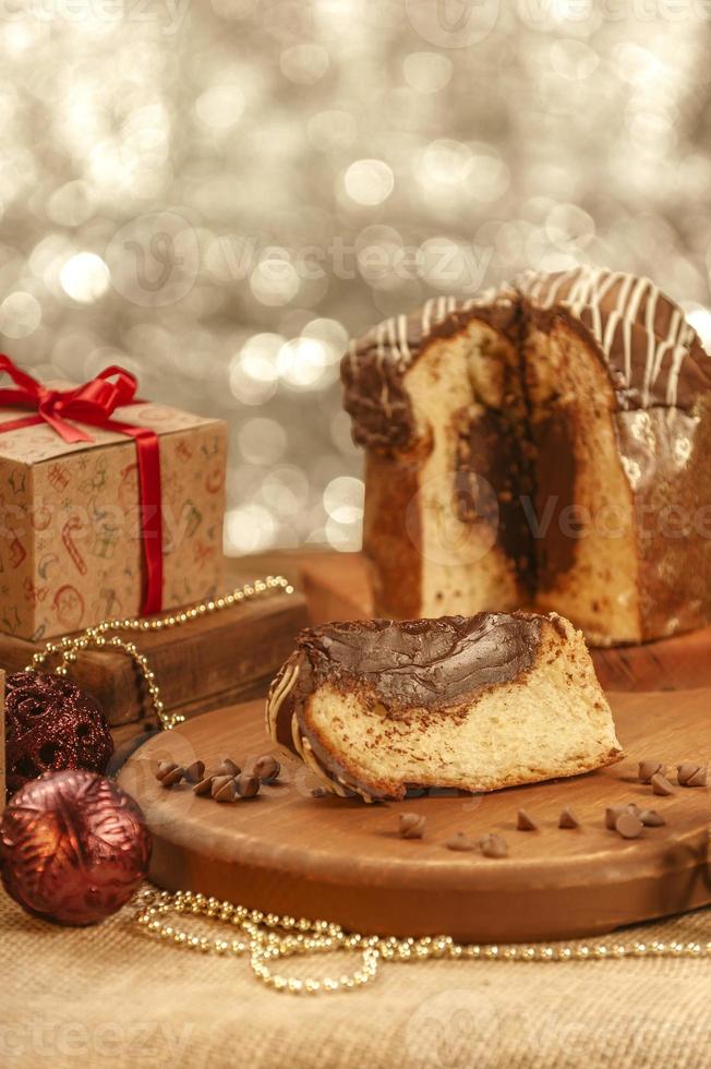 fetta di panettone al cioccolato su tagliere in legno con addobbi natalizi foto