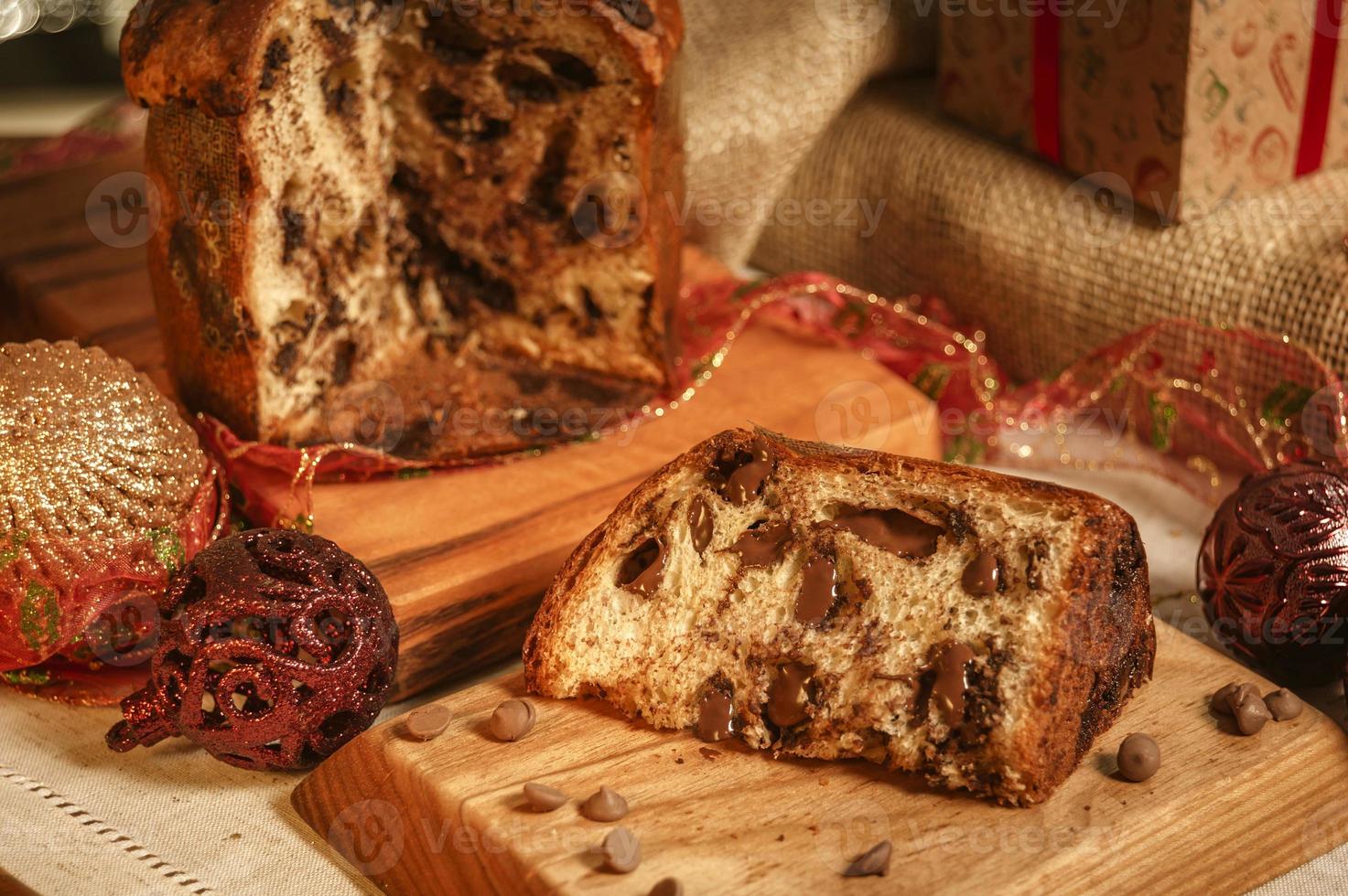 fetta di panettone al cioccolato su tagliere in legno con addobbi natalizi foto