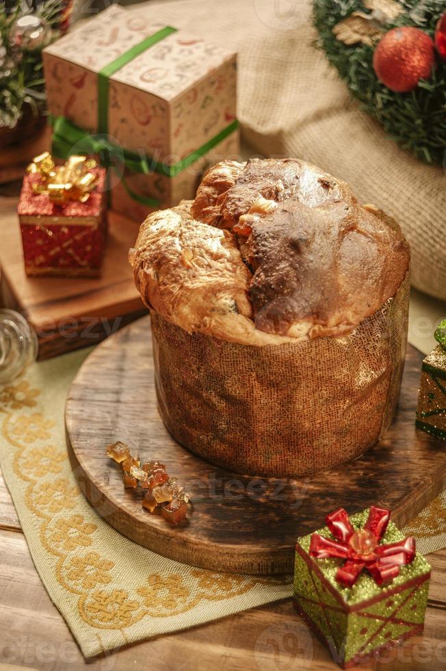 panettone, uvetta e cubetti di frutta candita su tagliere in legno con addobbi natalizi foto