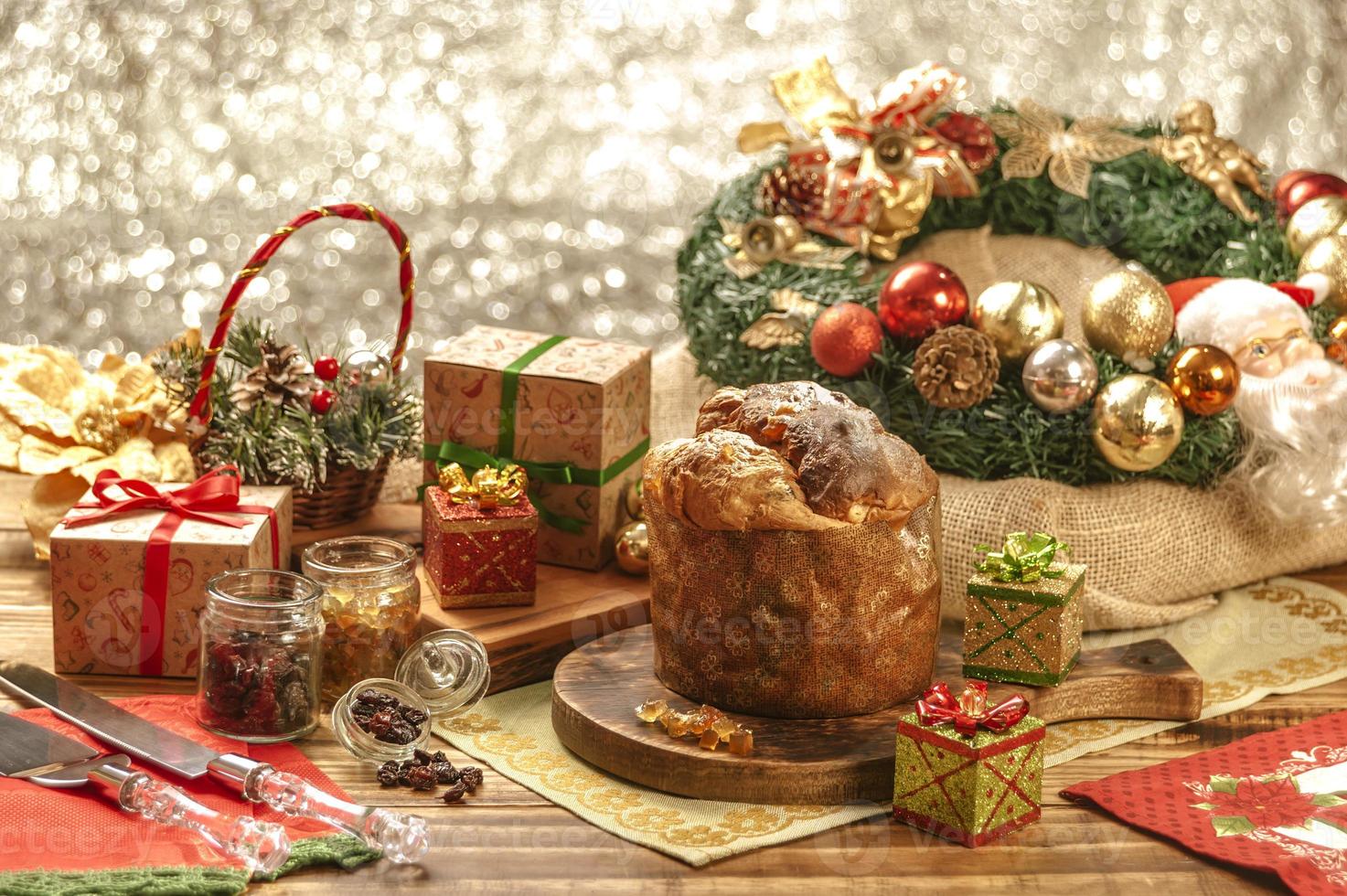 panettone, uvetta e cubetti di frutta candita su tagliere in legno con addobbi natalizi foto