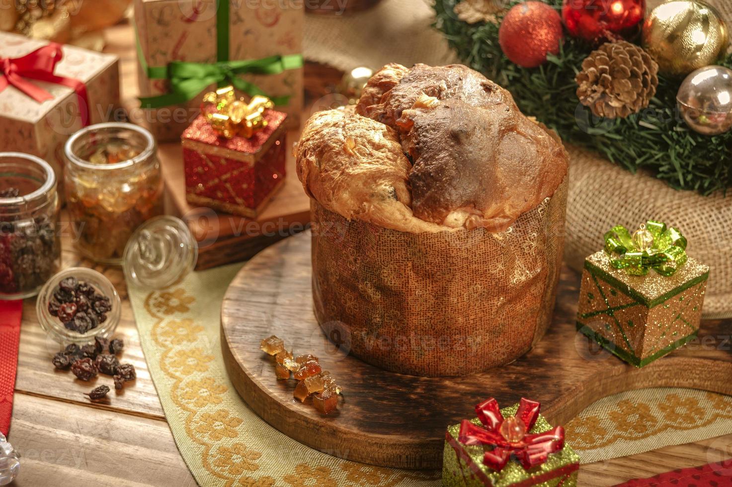 panettone, uvetta e cubetti di frutta candita su tagliere in legno con addobbi natalizi foto