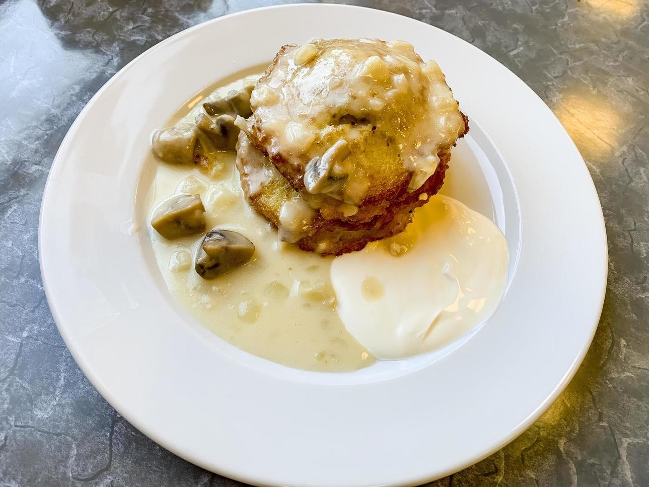 frittelle di patate, salsa con funghi nel piatto bianco. foto in studio.