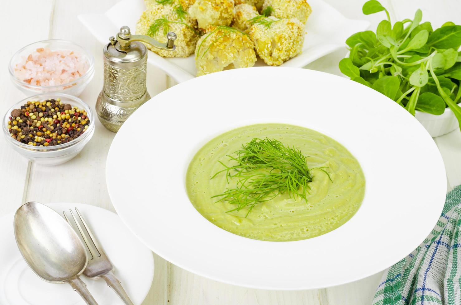 piatto bianco con zuppa cremosa di verdure verdi, piatto dietetico sano. foto