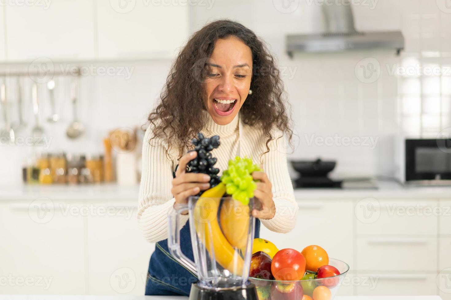 donna latina che fa il succo in cucina foto