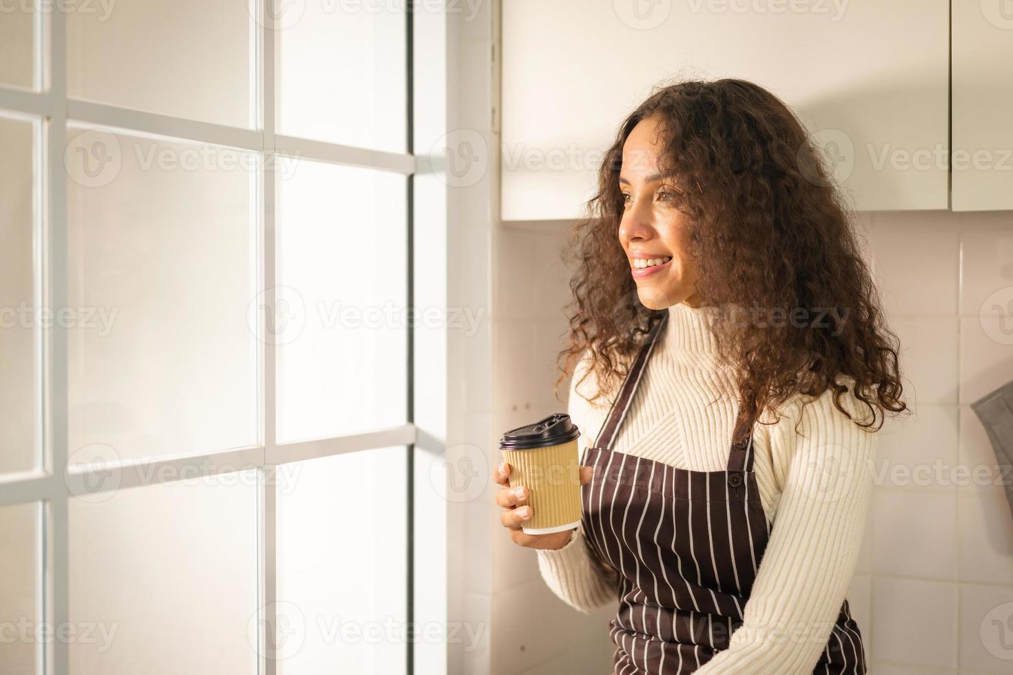 donna latina che beve caffè in cucina foto