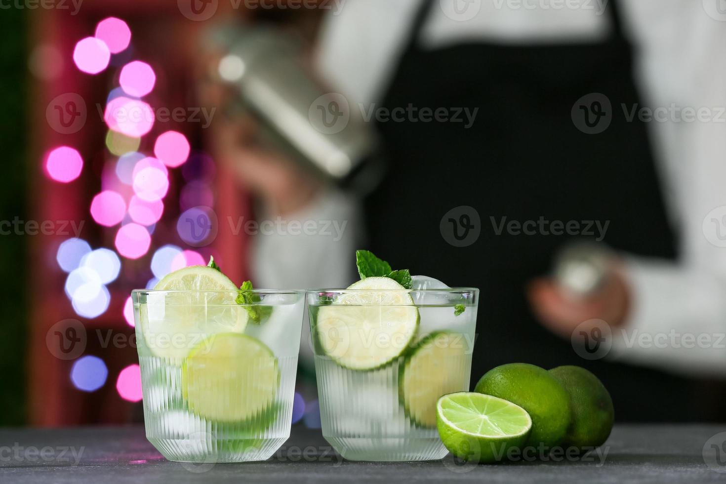 Barista con bicchieri di mojito fresco sul tavolo in bar foto