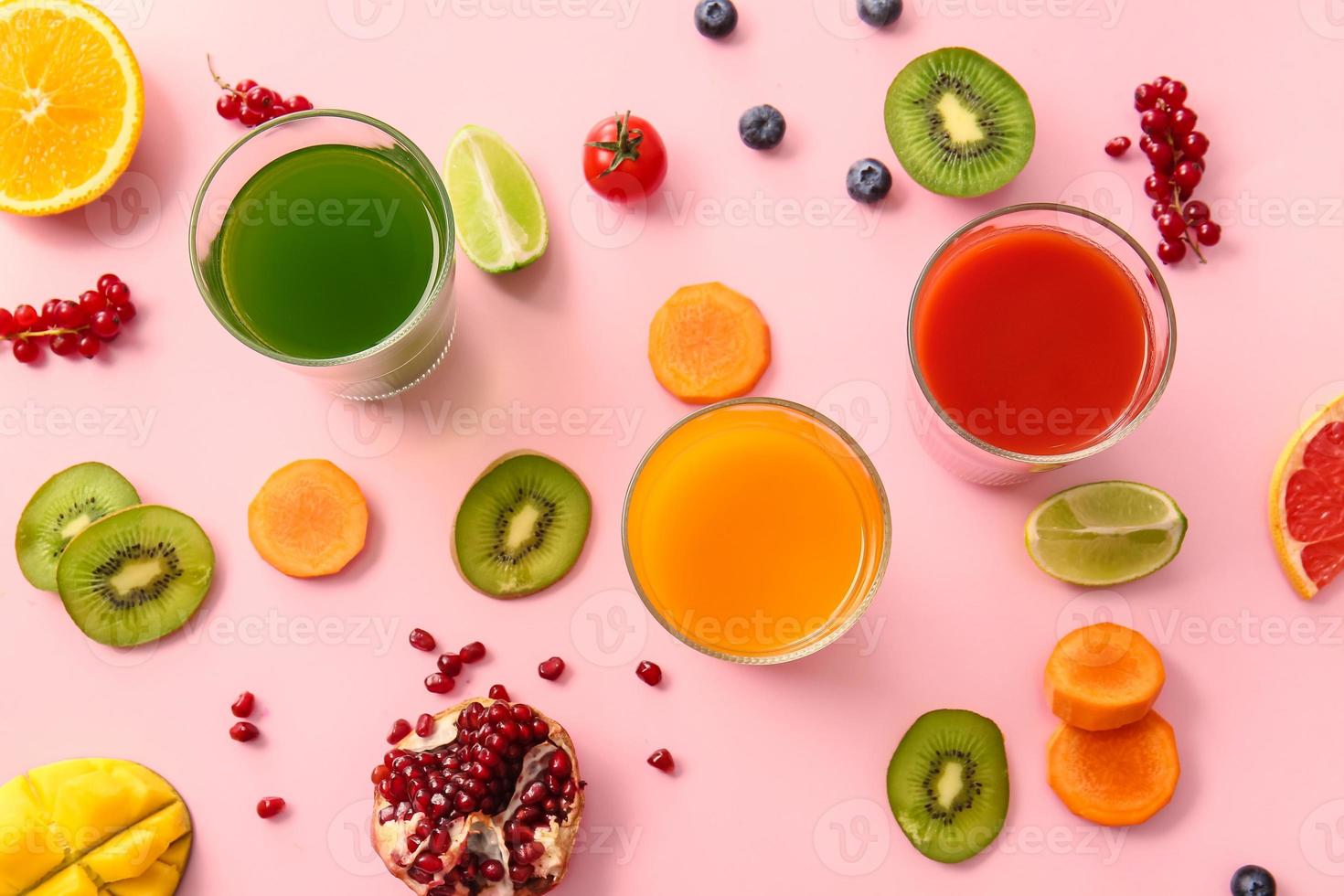 bicchieri con succo sano, frutta e verdura su sfondo colorato foto