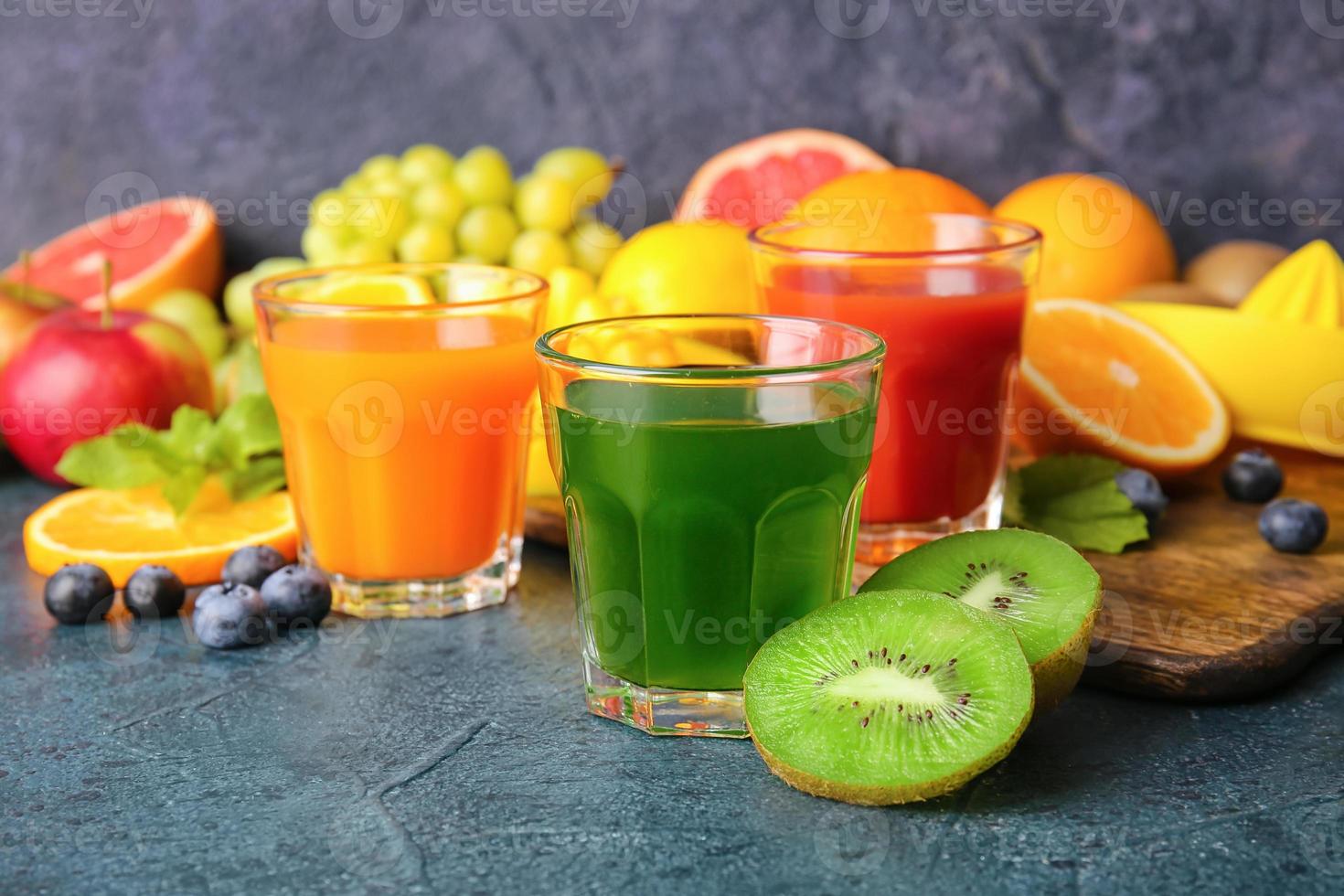 bicchieri con succo sano, frutta e verdura su sfondo scuro foto