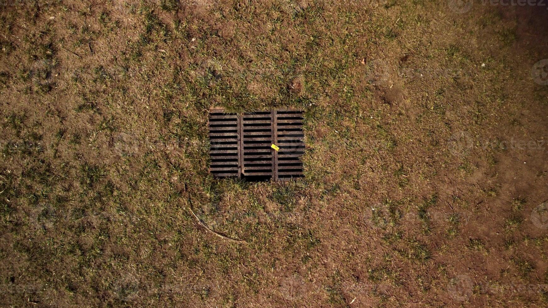 superiore aereo Visualizza su asciutto giallo erba, terra e drain fogna griglia nel terra. foto