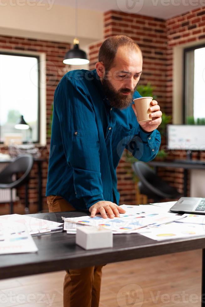 uomo d'affari che guarda lo schermo del laptop analizzando il rapporto sulla strategia aziendale foto