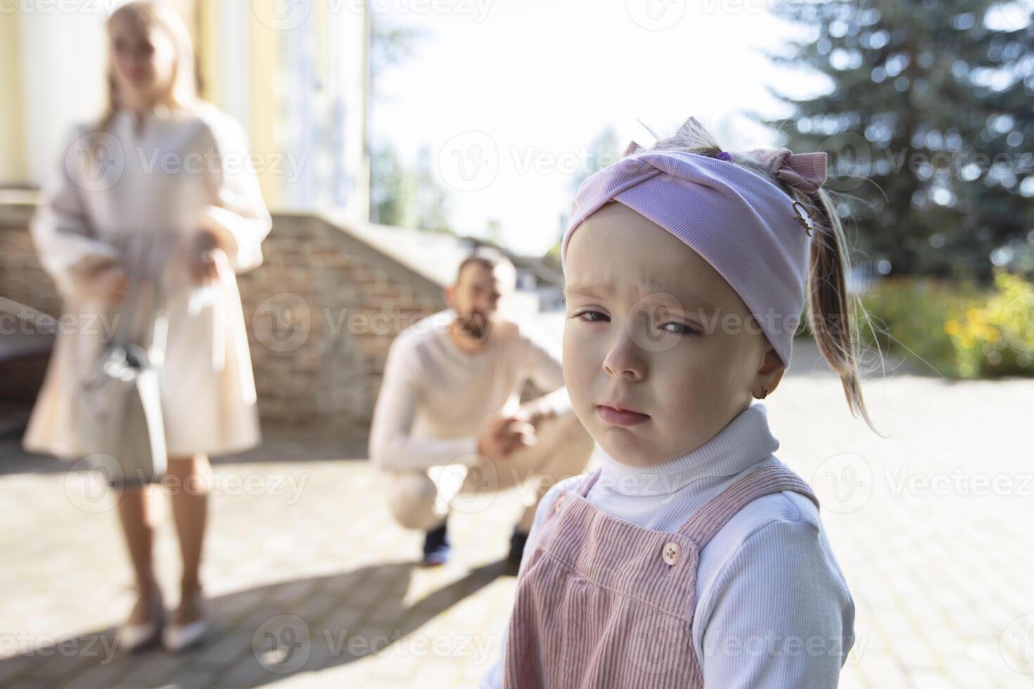 psicologico ritratto di un' insoddisfatto triste bambino contro il sfondo di sfocato genitori. le difficoltà nel raccolta giovane bambini. foto