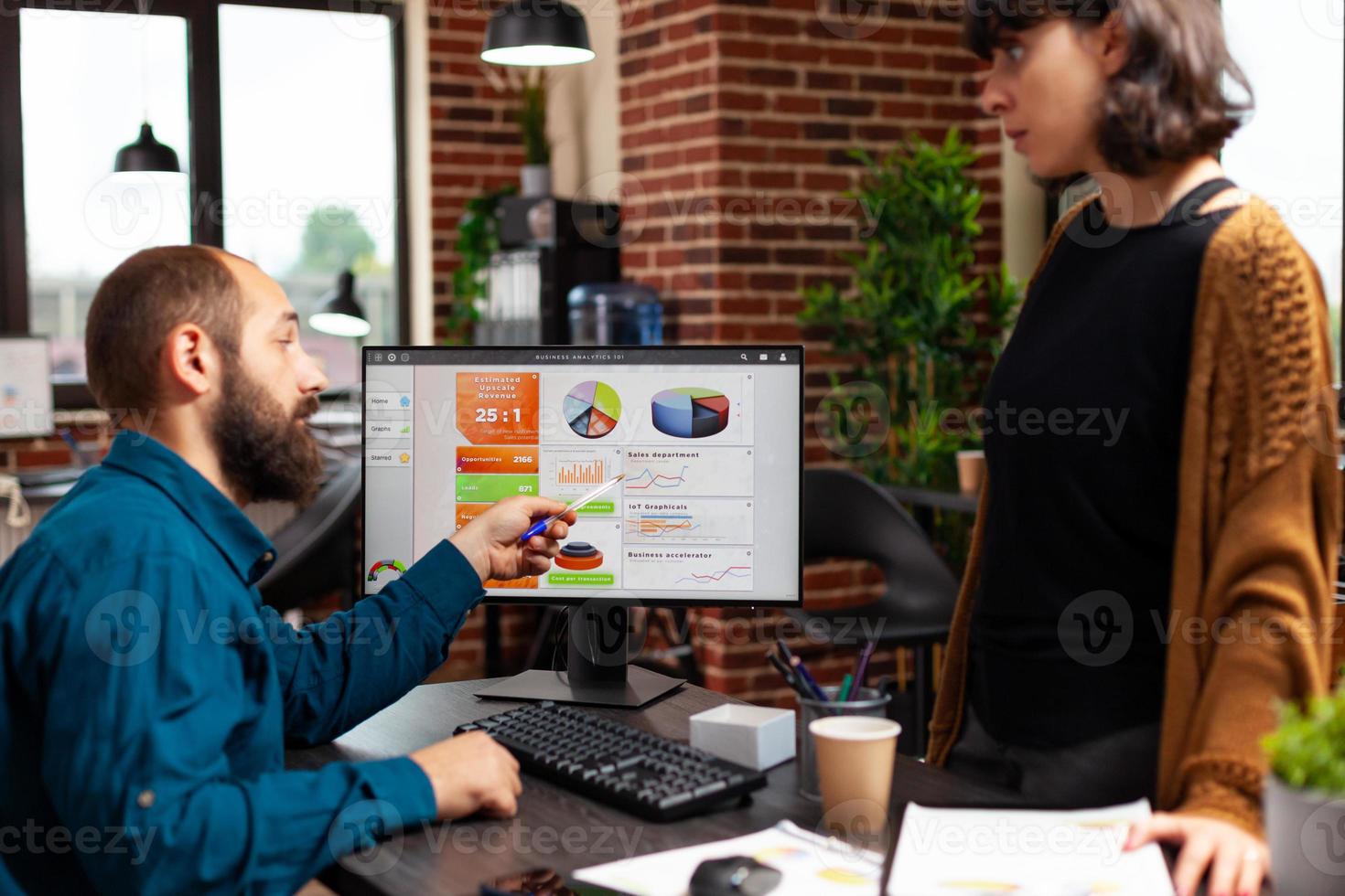 uomo d'affari che spiega la strategia di marketing al manager donna che mostra il grafico dei dati dell'azienda foto