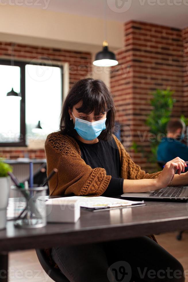 donna contabile con maschera protettiva medica contro il covid19 che analizza la strategia aziendale foto