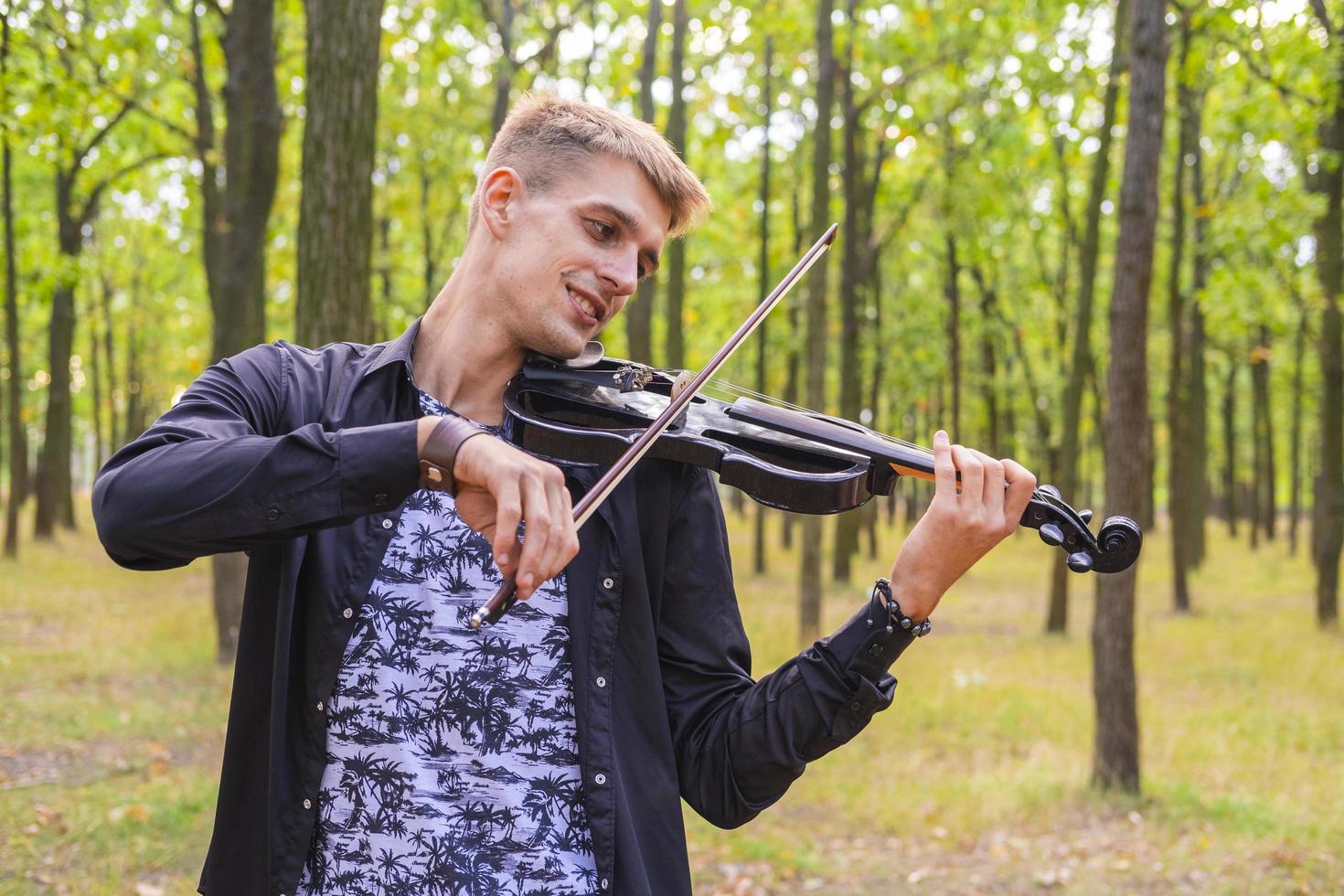 giovane maschio suona il violino nel parco estivo foto