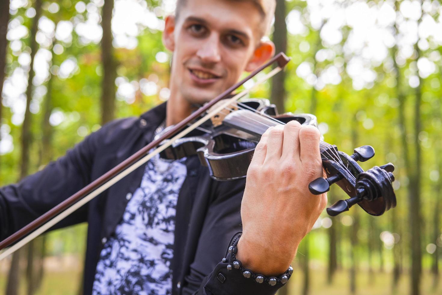 giovane maschio suona il violino nel parco estivo foto