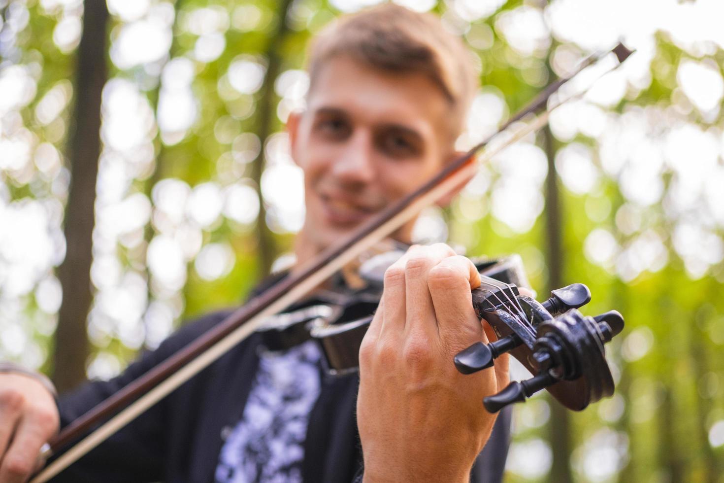 giovane maschio suona il violino nel parco estivo foto