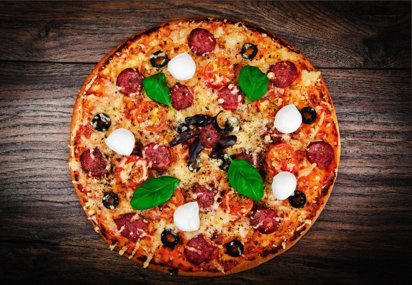 pizza ai peperoni con salsiccia, formaggio, mozzarella, olive e bas foto