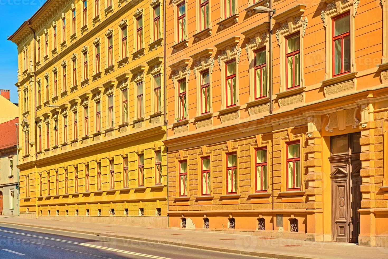 una classica facciata di un vecchio edificio dipinta nei colori giallo e arancione. edificio residenziale su una strada vuota foto