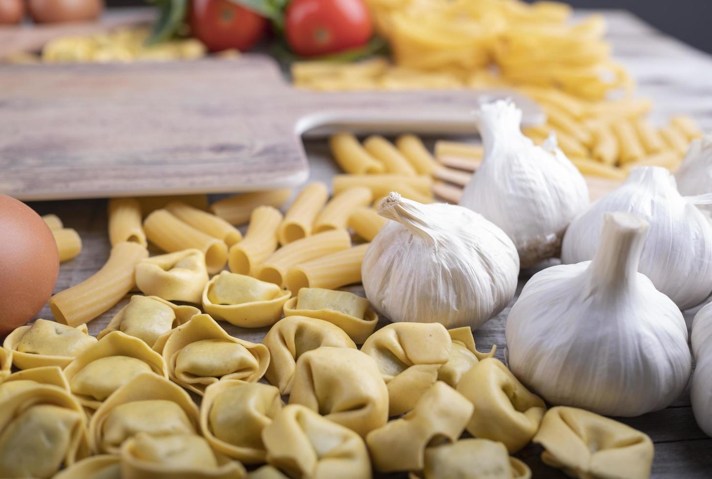 set di pasta, verdure, aglio, ingredienti del ristorante italiano, tagliere foto