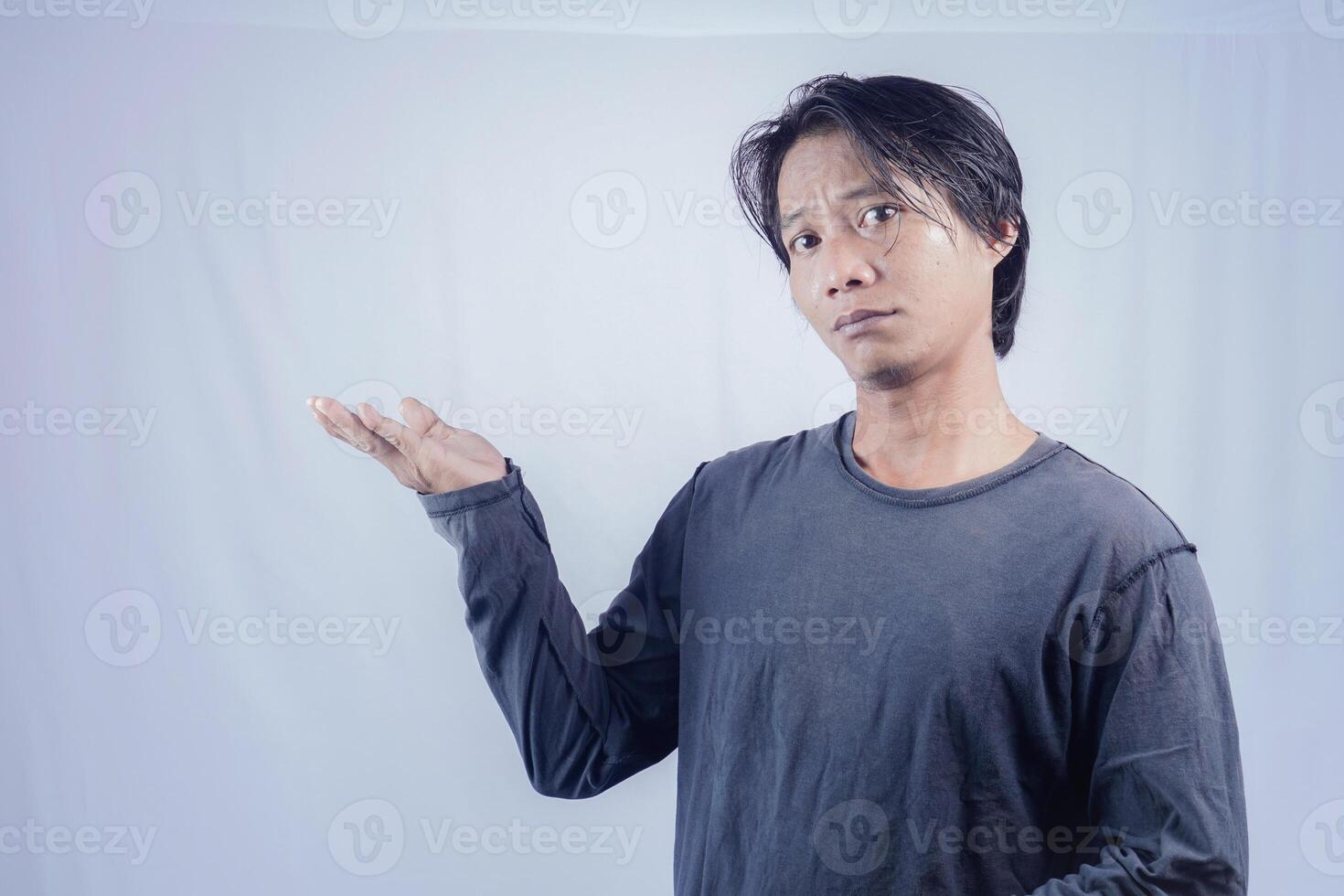 bello asiatico uomo di fronte il telecamera è puntamento a il copia spazio per pubblicità su un isolato bianca sfondo. foto
