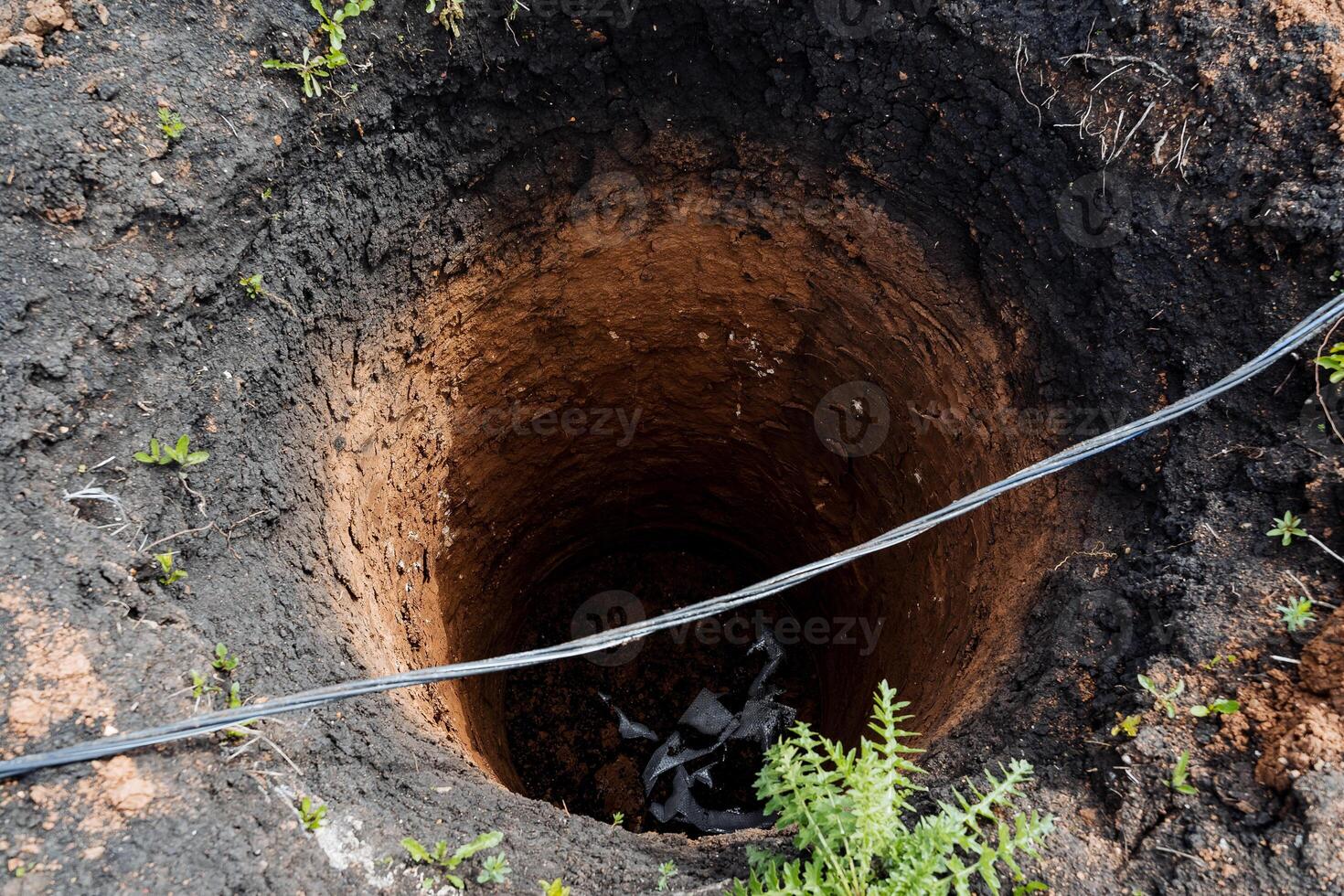 un' buco scavata per un' bene, un' in profondità il giro bene, un' pozzo nero, un' giardino fogna, perforazione, gocciolante il terra. foto