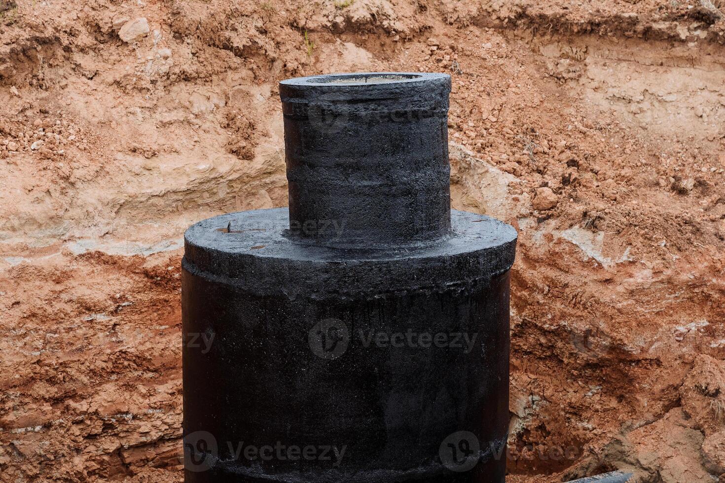 il fogna bene è coperto con nero impermeabilizzazione, calcestruzzo protezione con bitume, un' fossa per rete fognaria, un' argilla fosso, riparazione di un' acqua canale, installazione di rinforzata calcestruzzo anelli. foto