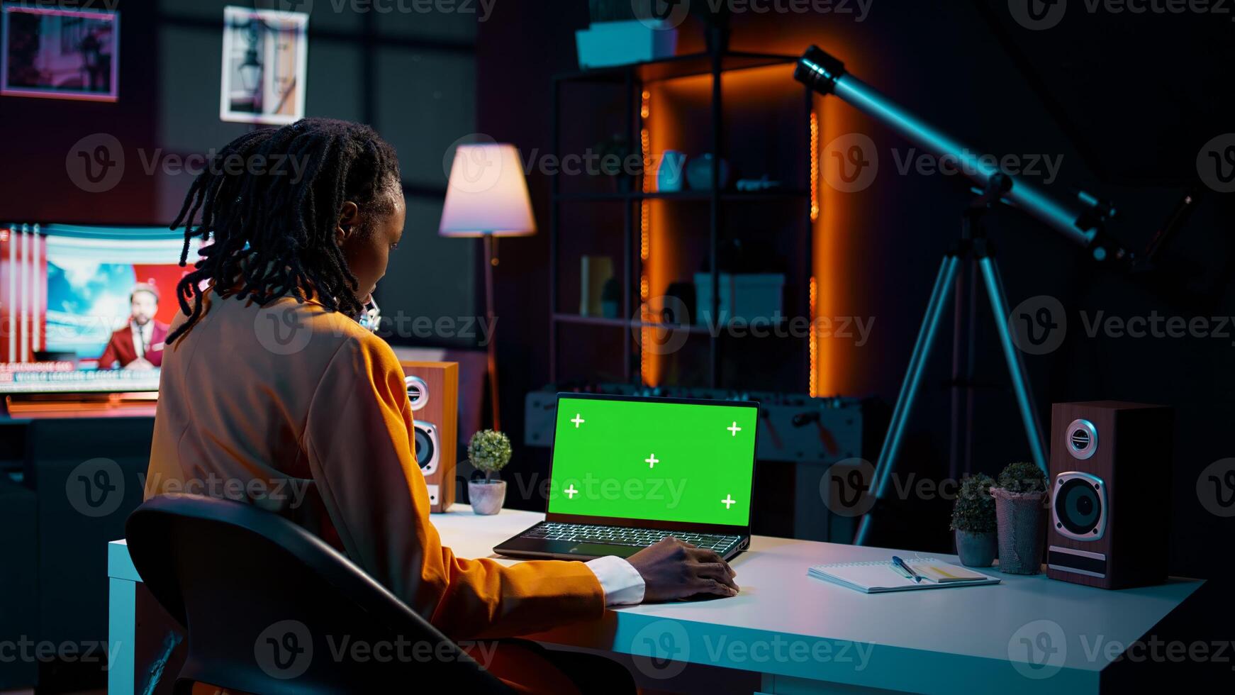 africano americano giovane donna sembra a il computer portatile con schermo verde, seduta a sua casa scrivania e preparazione per assistere in linea Università Lezioni. ragazza utilizzando pc con isolato modello disposizione. telecamera b. foto