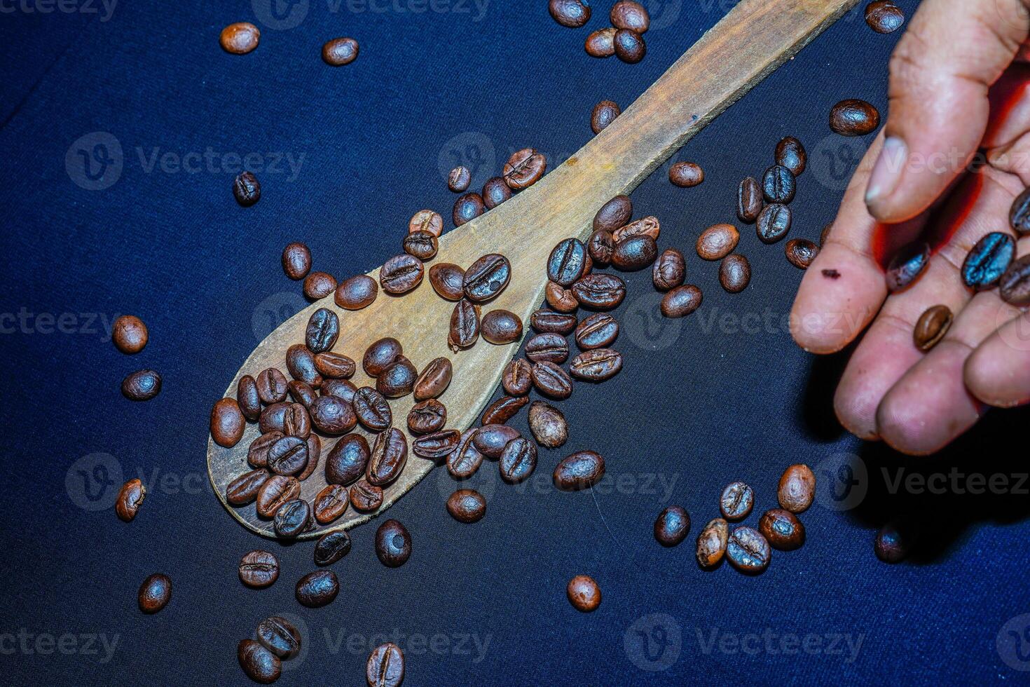 nero caffè fagioli siamo visto vicino su con un' di legno cucchiaio su un' nero stoffa. foto