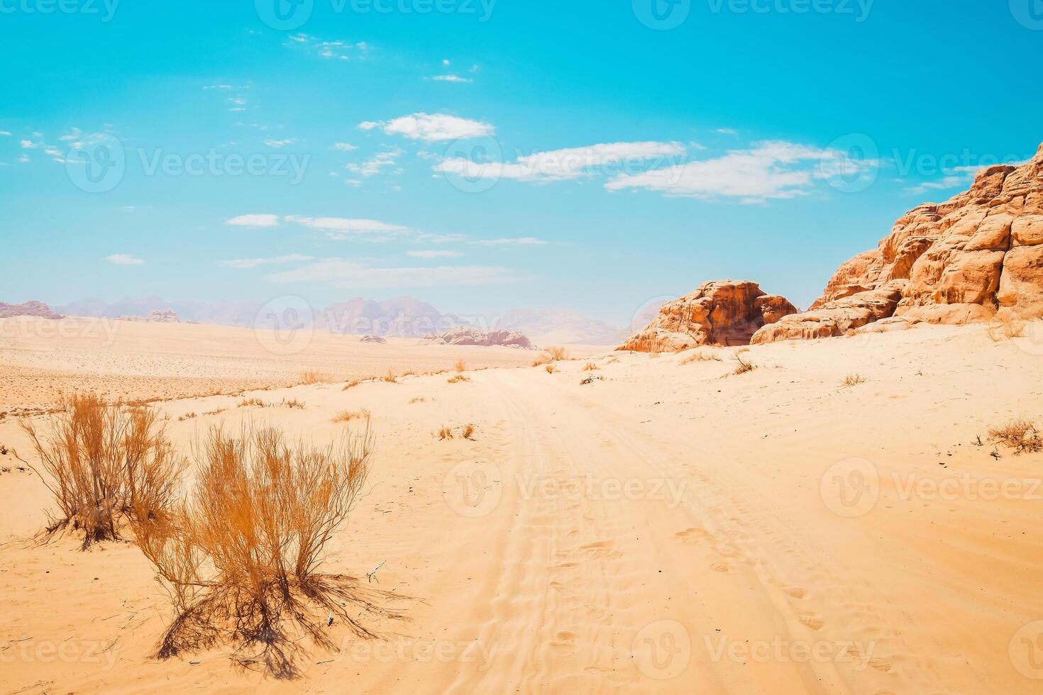 panoramico wadi Rum deserto panorama nel caldo soleggiato giorno con auto brani su sabbia. famoso le riprese posizioni di film foto