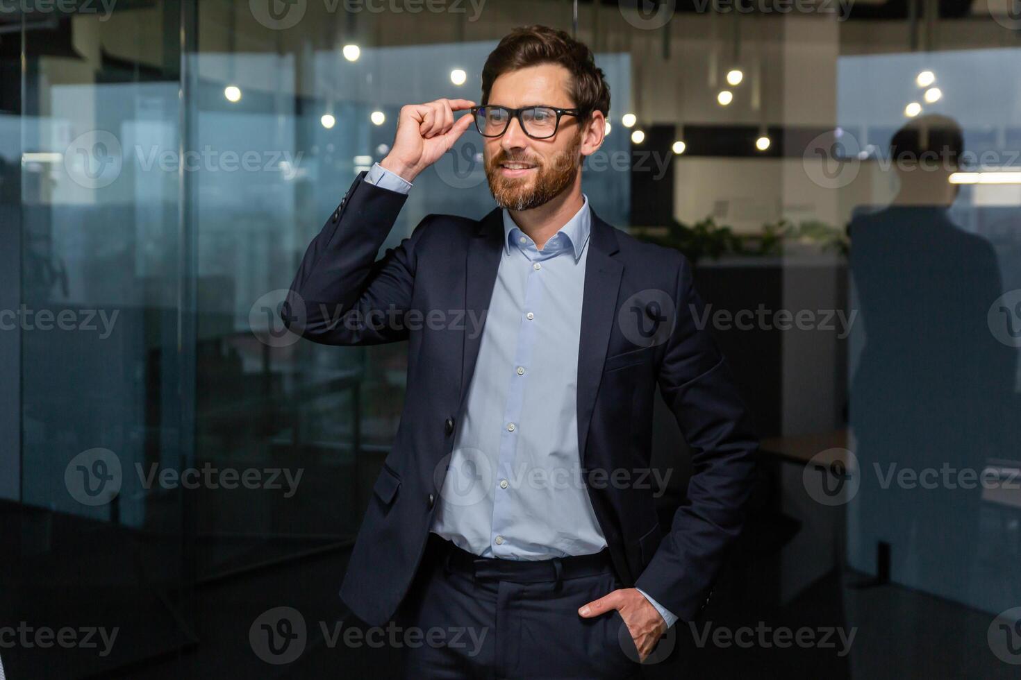 ritratto di riuscito uomo d'affari maturo capo nel attività commerciale completo da uomo, uomo Lavorando dentro ufficio a opera nel bicchieri guardare lontano, anziano investitore con barba sorridente e sognante. foto