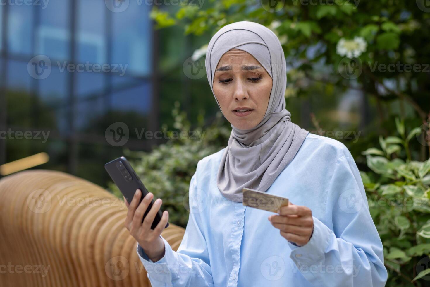 irritato imbrogliato donna con Telefono provando per rendere in linea Acquista e i soldi trasferimento, musulmano donna nel hijab deluso avuto rifiuto, Tenere Telefono e banca credito carta, insoddisfatto acquirente. foto