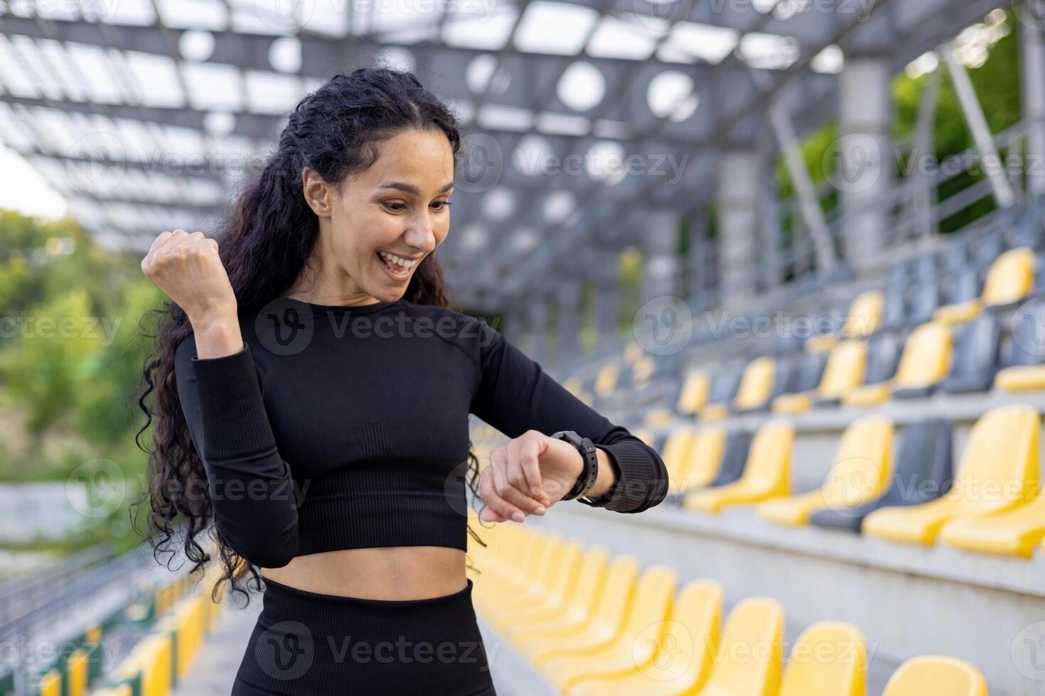 incentrato sul fitness donna nel atletico indossare utilizzando un' orologio intelligente a un' gli sport stadio, incarnando Salute e attivo stile di vita. foto