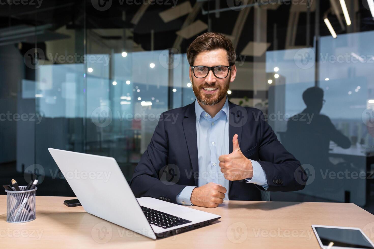 ritratto di maturo riuscito investitore, uomo d'affari nel attività commerciale completo da uomo Lavorando dentro ufficio utilizzando computer portatile, anziano maschio capo guardare a telecamera sorridente e mostrando pollici su. foto