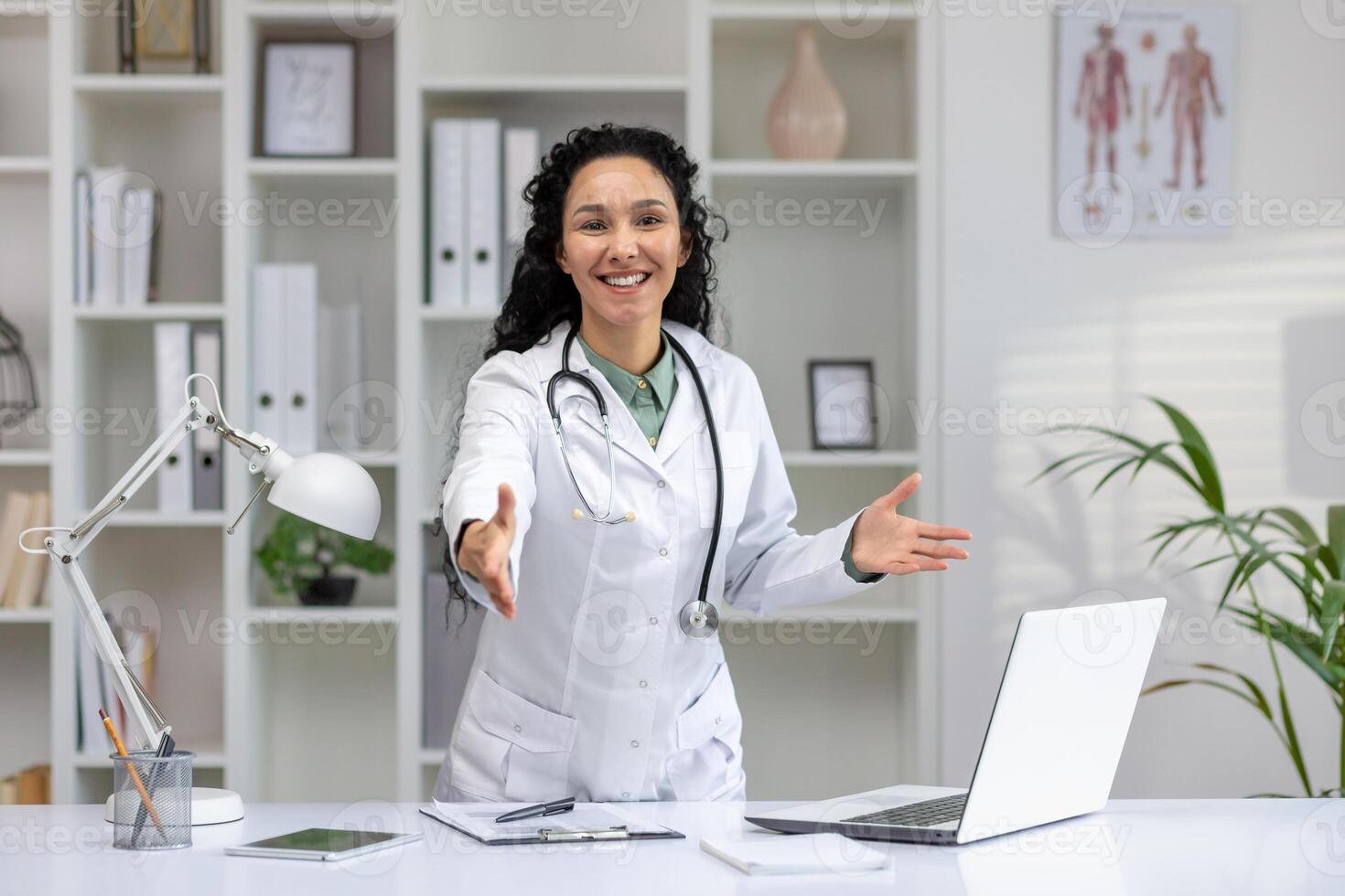 professionale latina medico con accogliente gesto nel un' luminosa medico ufficio, emanando fiducia e cura. foto