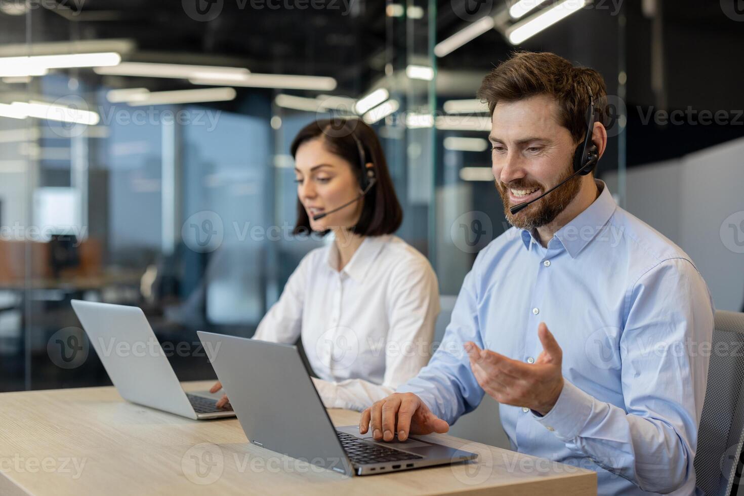 caucasico femmina e maschio nel aziendale vestito codice Abiti e cuffie con micro seduta di portatile computer. Due cliente cura lavoratori principale conversazione con clienti nel moderno ufficio. foto