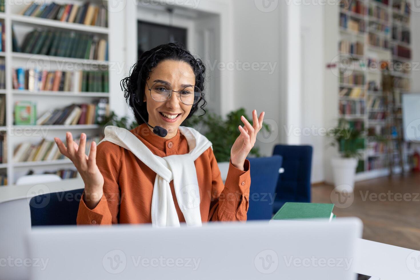 giovane bellissimo ispanico femmina insegnante insegnamento alunno studenti in linea a distanza, donna seduta a scrivania Lavorando nel accademico Università biblioteca, utilizzando il computer portatile e tavoletta per chiamata. foto
