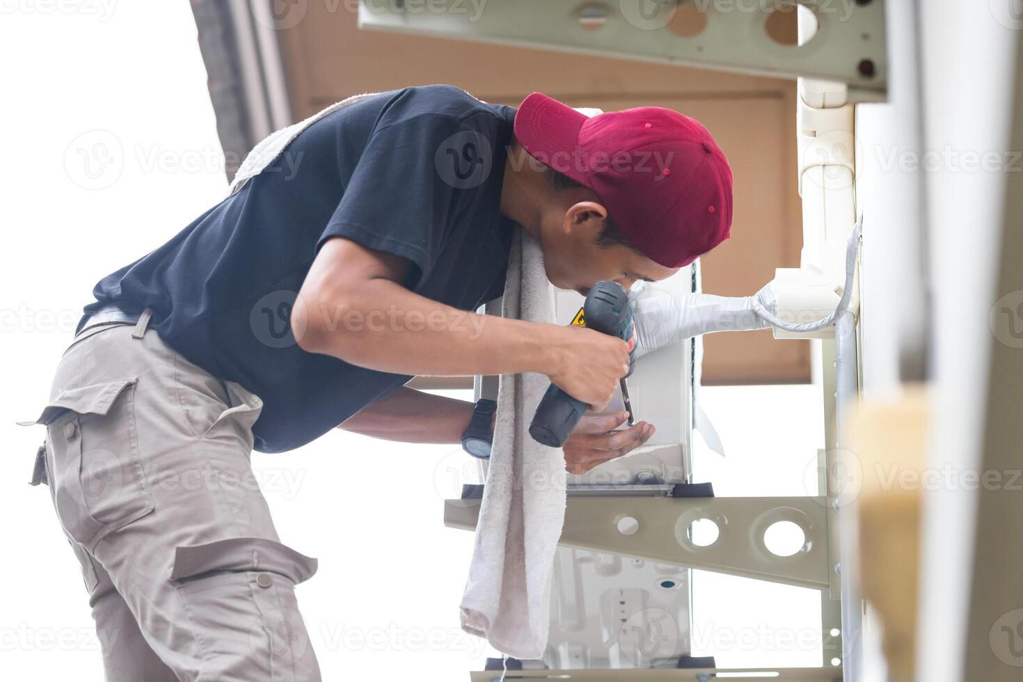 mani del tecnico maschio utilizzando un cacciavite che fissa il moderno condizionatore d'aria, la riparazione e l'assistenza, la manutenzione e il concetto di riparazione foto