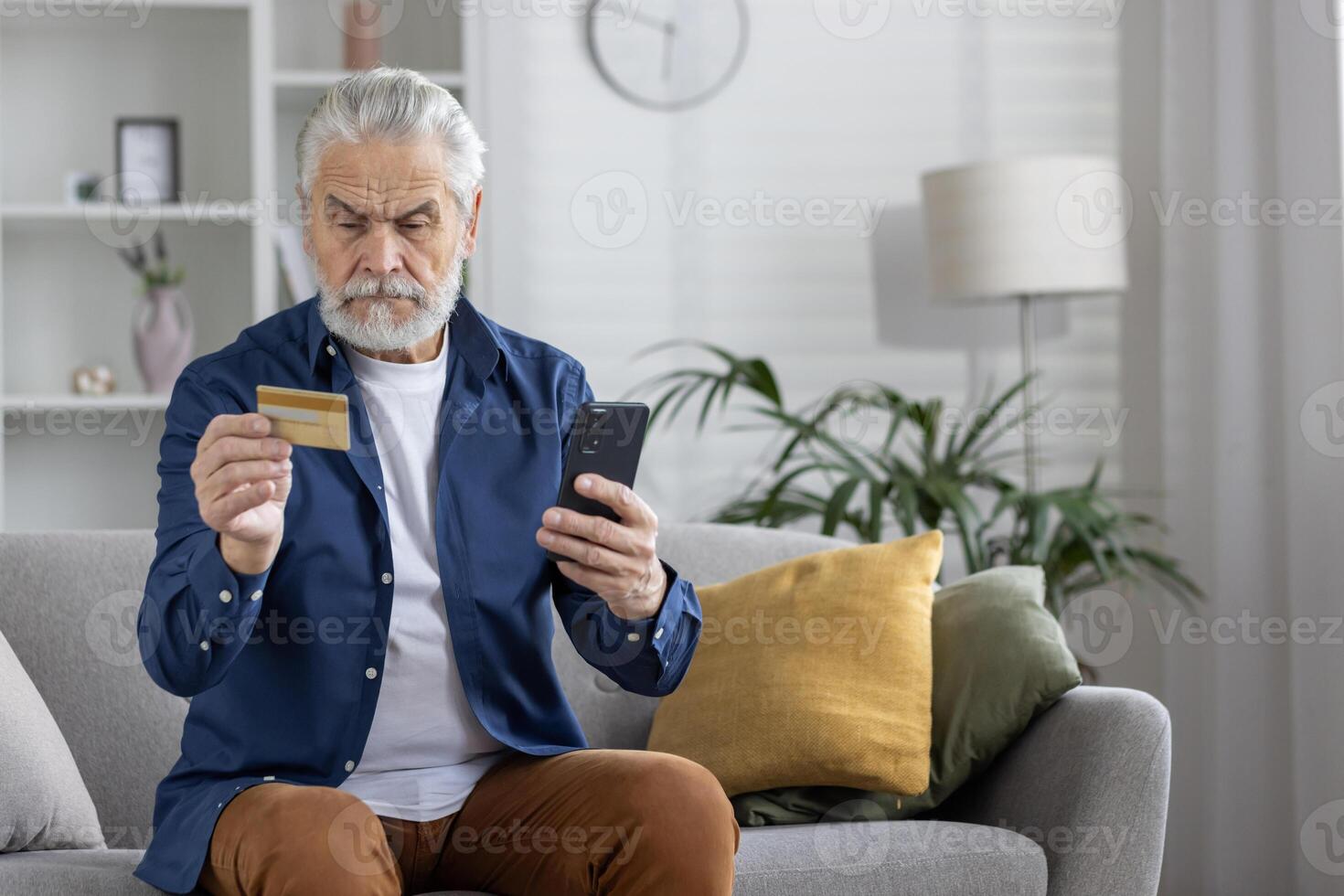 un' maturo adulto maschio comodamente utilizzando un' smartphone e credito carta per un' sicuro in linea transazione mentre seduta su un' divano a casa. foto