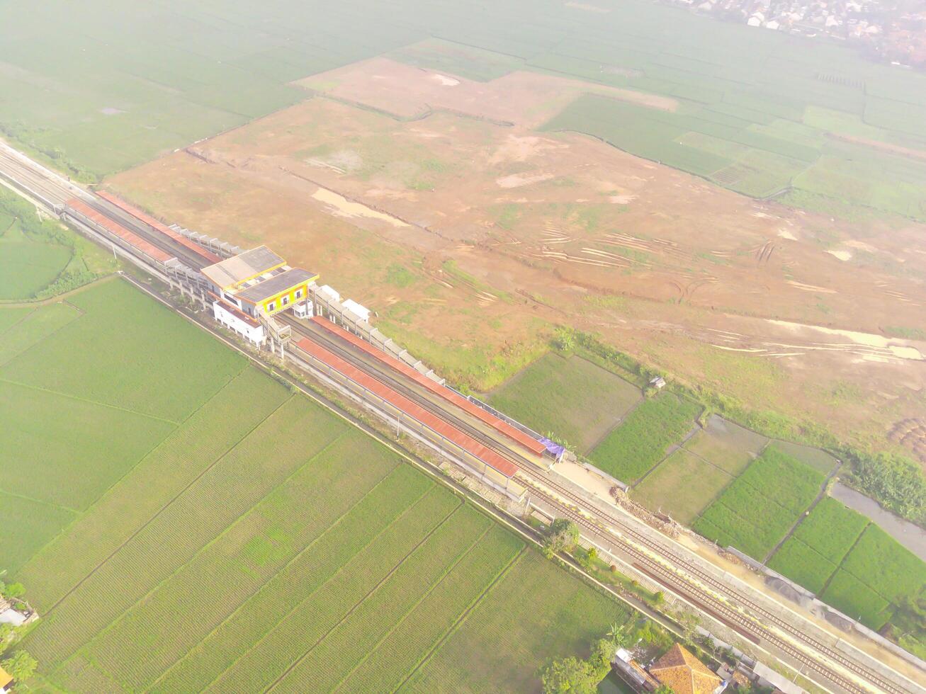 nebbioso Visualizza di il ferrovia linea. aereo Visualizza di treno traccia e stazione nel rancaekek, bandung - Indonesia. naturale condizioni. sopra. pubblico trasporto. tiro nel fuco volante 100 metri foto