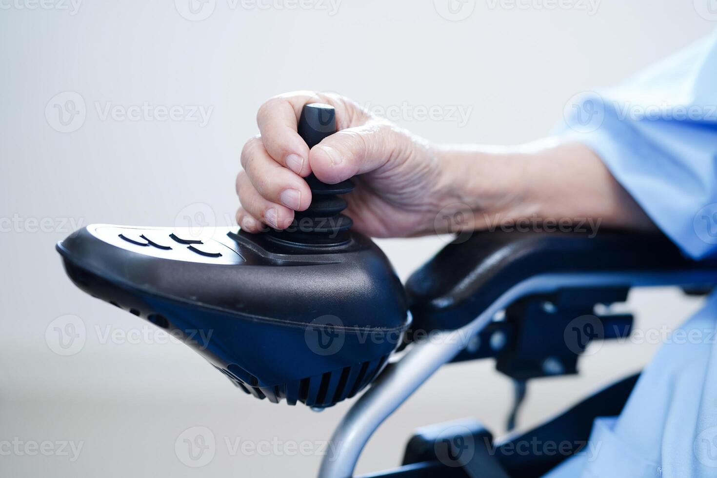 asiatico anziano invalidità donna paziente uso telecomando da gioco elettrico sedia a rotelle nel Ospedale. foto