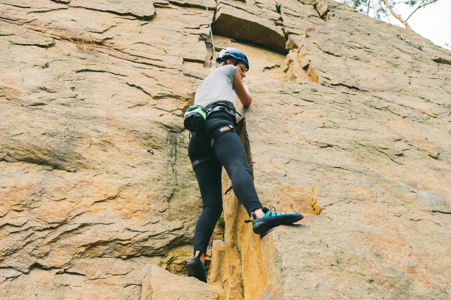 giovane atletico donna nel attrezzatura fare roccia arrampicata all'aperto. formazione la zona per all'aperto attività. estremo sport. foto