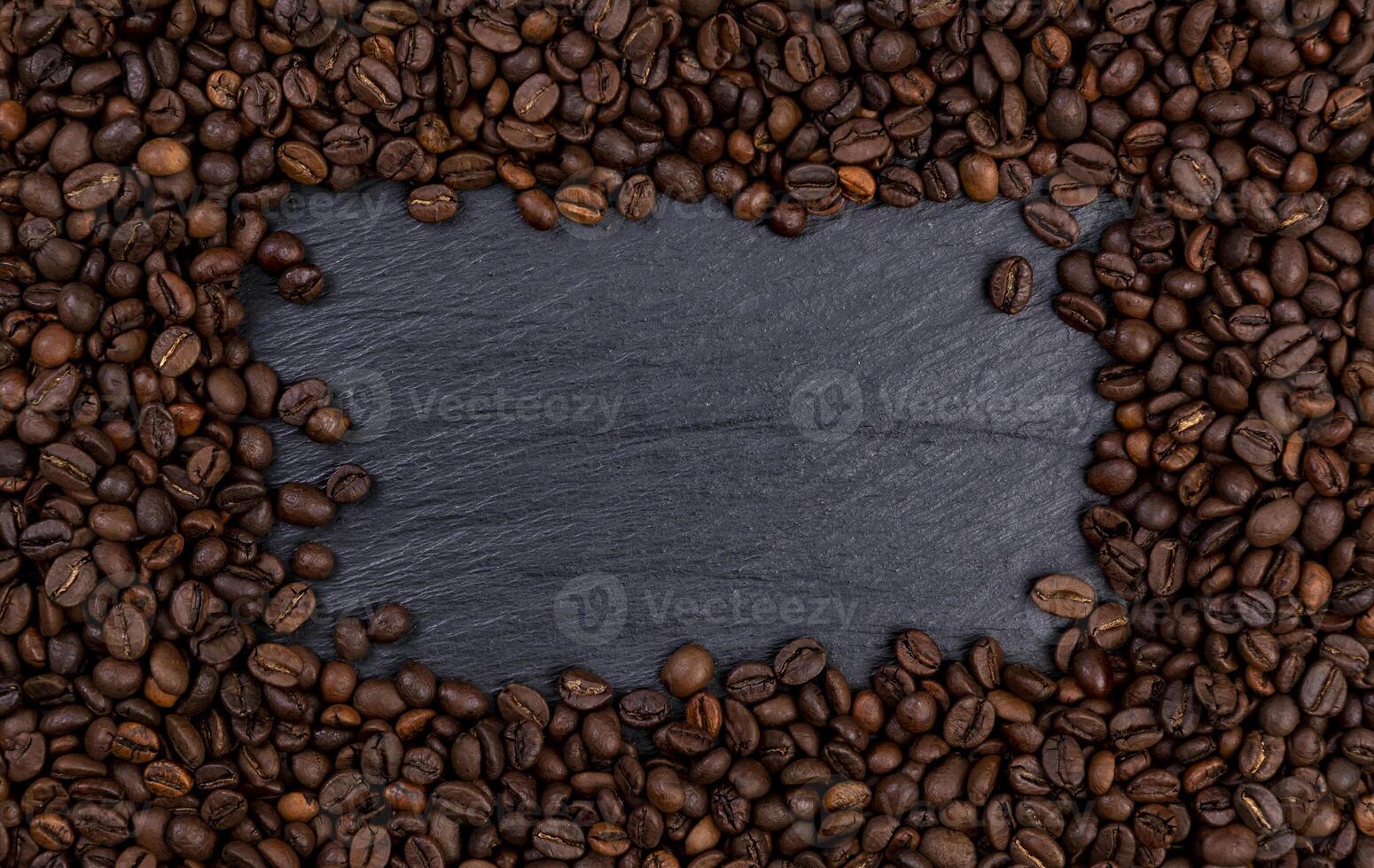 cornice fatta di chicchi di caffè tostati sul tavolo nero, vista dall'alto foto